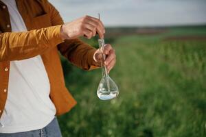 With test tube.... Close up view of man that is on the agricultural field at daytime photo