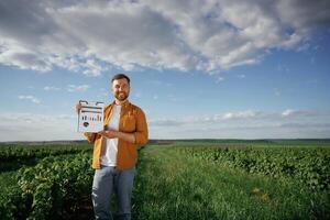 Graphs and,, business analytics on document, notepad. Handsome man is on the agricultural field at daytime photo