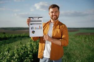 Graphs,and business ,analytics on document, notepad. Handsome man is on the agricultural field at daytime photo