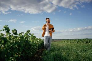 Talking by,, phone, holding notepad. Handsome man is on the agricultural field at daytime photo