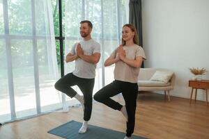 Man and woman, are ,,doing yoga exercises at home photo