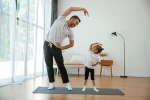 Spine exercise. Father with ,,little ,daughter are doing yoga at home photo