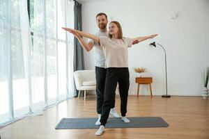 Man and woman are doing,, yoga, exercises at home photo