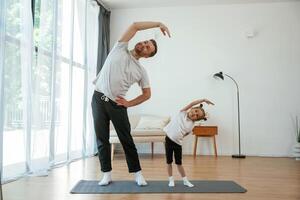 Spine ,,exercise. Father with little daughter are doing yoga at home photo
