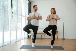 Man and woman are ,doing,, yoga exercises at home photo