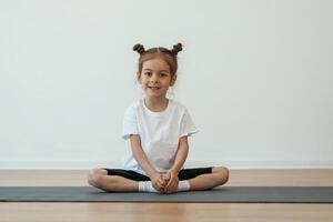 Cute little ,girl ,,is sitting on the yoga mat and doing exercises photo