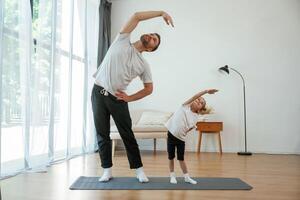 Spine exercise. Father with little ,daughter are doing yoga at home photo