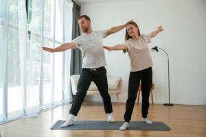 Man and woman are ,doing yoga exercises at home photo