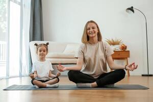 Smiling, positive, facia,l expression. Young woman with little girl are doing yoga at home photo