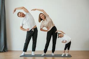 Warm up ,exercises. Family of mother, ,father and daughter are doing yoga at home photo
