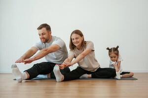 Family of, mother, father and ,daughter are doing yoga at home photo