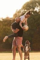 Girlfriend ,is with, soccer ball.. Man and woman are with dog on the field photo