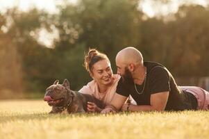 Calm, ,lying ,,down on the ground. Man and woman are with dog on the field photo