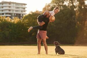 Girlfriend ,is with soccer,, ball. Man and woman are with dog on the field photo