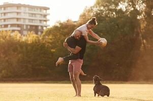Girlfriend is with soccer ball. Man and woma,n are with dog on the field photo