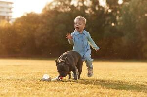 Running together. Cute little boy,, is, with dog on the field photo