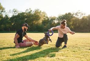 Active, time, spending, with rubber toy. Man and woman are with dog on the field photo