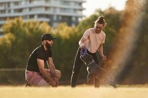Active time spending,, with rubber toy. Man and woman are with dog on the field photo