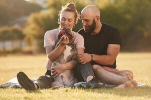 Having a rest, sitting. Man and, woman ,are with dog on the field photo