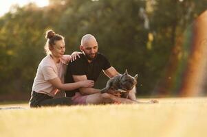 Man and ,woman are with ,,dog on the field photo