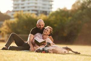 Having a rest, sitting... Man and ,woman are with dog on the field photo