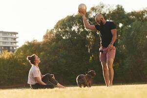 Golden ,colored soccer, ball in hand. Man and woman are with dog on the field photo