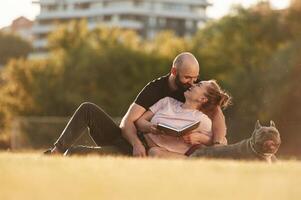 Having a rest,,, sitting. Man and woman are with dog on the field photo