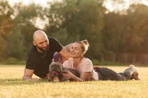 Positive facial expression, ,,resting. Man and woman are with dog on the field photo