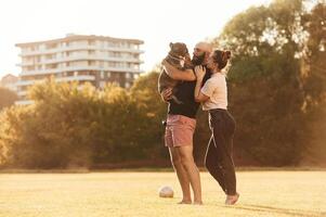 Side ,view,, standing and holding animal. Man and woman are with dog on the field photo