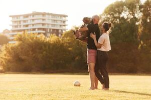 Side view, standing ,and holding animal. Man and woman are with dog on the field photo