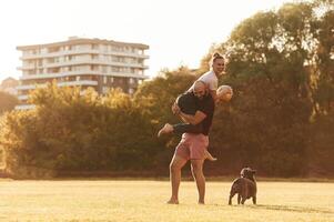 Girlfriend, is with soccer ball. Man and woman are with dog on the field photo