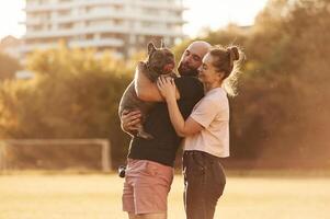 Side ,view, standing and holding animal. Man and woman are with dog on the field photo