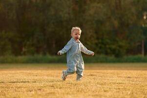 Having, fun, running. Little boy is on the summer field photo