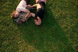 Top, view, lying ,on the grass. Man and woman are with dog on the field photo