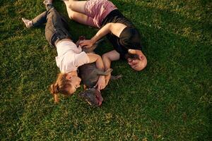 On, the grass, lying down. Man and woman are with dog on the field photo