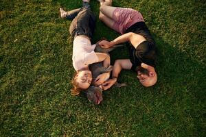 On the, grass, lying down. Man and woman are with dog on the field photo