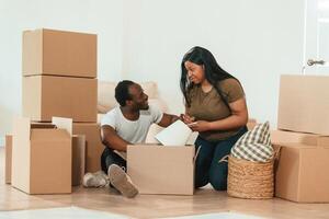 Making ,notes ,into ,notepad. African American couple are moving into new house photo