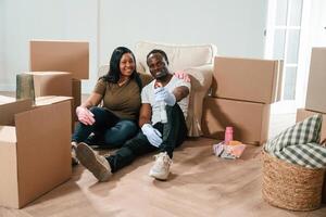 With product for cleaning the, floor ,and surfaces. African American couple are moving into new house photo