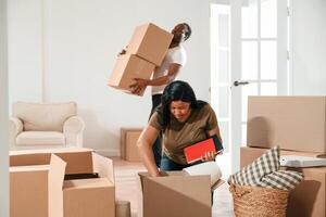 Guy is holding lot of, boxes. African American couple are moving into new house photo