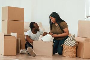 Making, notes into, notepad. African, American couple are moving into new house photo