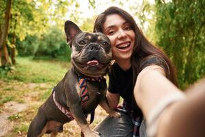 Making a selfie. Young pretty woman is with her dog in the ,park photo