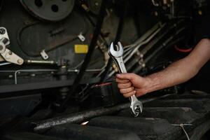 Close up, view... Mechanic's hand fixing machinery with wrench in workshop photo