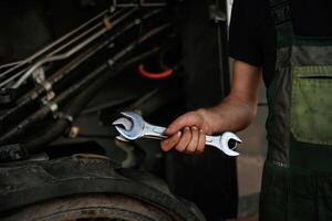 Close up view.. Mechanic's,, hand fixing machinery with wrench in workshop photo