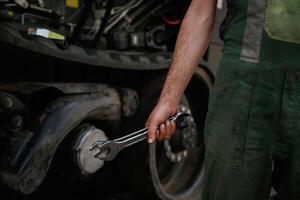 Holding, wrench. Mechanic's hand fixing machinery in workshop., photo