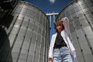 Looking far away. ..Confident worker standing in front of industrial silos under clear blue sky photo