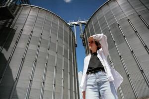Looking far away. ,.Confident worker standing in front of industrial silos under clear blue sky photo