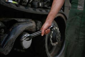Holding, wrench. Mechanic's hand fixing machinery in workshop. photo