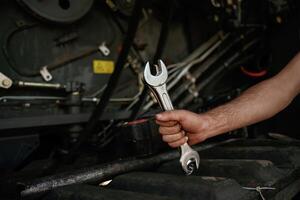 Close up view,. Mechanic's hand fixing machinery with wrench in workshop photo