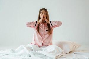Rest conception, waking up, on the white blanket. Young pretty woman is against background in the studio. photo