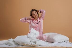 Front ,view, in ,pink pajama, waking up. Young pretty woman is against background in the studio photo
